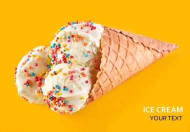 Dondurma topları renkli şeker sprinkles bir gözleme koni üzerinde sarı bir arka plan ile. Vanilyalı dondurma waffle koni.