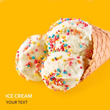 Dondurma topları renkli şeker sprinkles bir gözleme koni üzerinde sarı bir arka plan ile. Vanilyalı dondurma waffle koni.