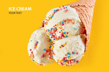 Dondurma topları renkli şeker sprinkles bir gözleme koni üzerinde sarı bir arka plan ile. Vanilyalı dondurma waffle koni.