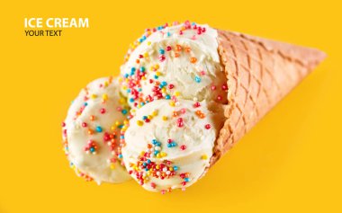 Dondurma topları renkli şeker sprinkles bir gözleme koni üzerinde sarı bir arka plan ile. Vanilyalı dondurma waffle koni.