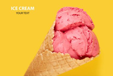 Bir Waffle koni sarı bir arka plan üzerinde pembe dondurma topları. Meyve dondurma waffle koni.