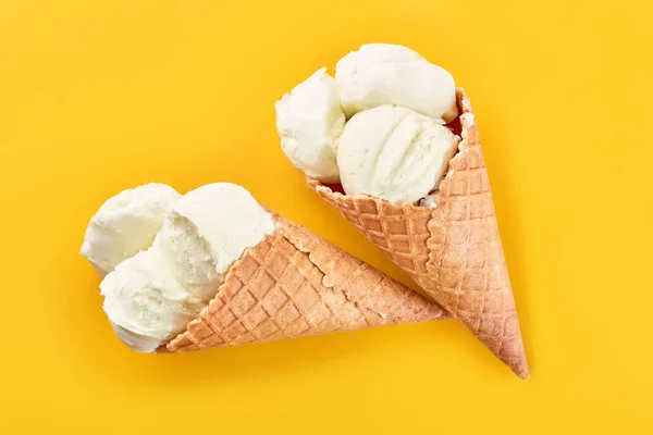 ice cream balls in a Waffle Cone on a yellow Background. Vanilla ice cream in a waffle cone.