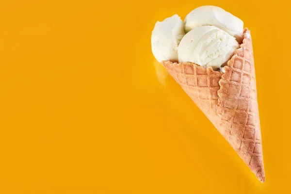ice cream balls with colored sugar sprinkles in a Waffle Cone on a yellow Background. Vanilla ice cream in a waffle cone.