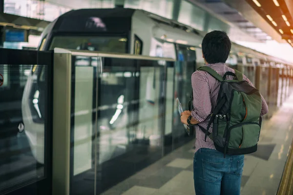 Cityscape Kuala Lumpur arka plan ile kitle hızlı Transit (Mrt) tren bekleyen genç Asya seyahat. Kuala Lumpur, Malezya demiryolu sisteminin büyük bileşeni oluşturan Mrt sistem.