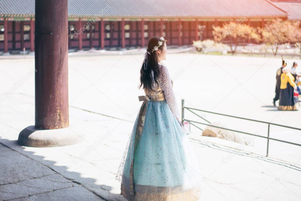 Young asian woman traveler in korean national dress or Hanbok walking traveling into the Gyeongbokgung Palace at Seoul city, South Korea.