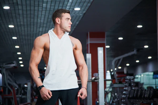 Fitness salonunda yakışıklı adam kameraya poz. Kusursuz bir beden ile uygun kaslı adam egzersiz için hazır hale getirilir. Fitness, welness ve aktif yaşam tarzı kavramı.