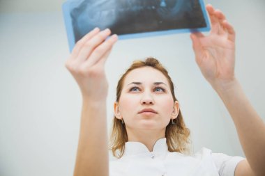 Kadın dişçi, insan çenesinin röntgenini inceliyor. Profesyonel stomatolog klinikteki diş röntgeni görüntülerini kontrol ediyor..