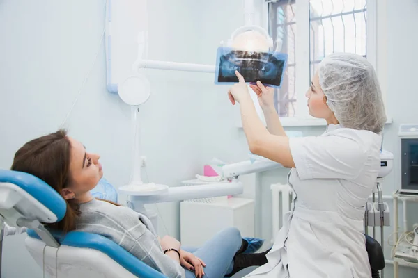 Kadın doktor diş hekimi insan çene x-ray incelenmesi. Profesyonel stomatologist gösteren diş röntgen görüntüye hasta klinik ofis.