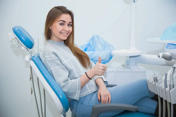 Satisfied female dentist patient after treatment in a clinic box with medical equipment in the background