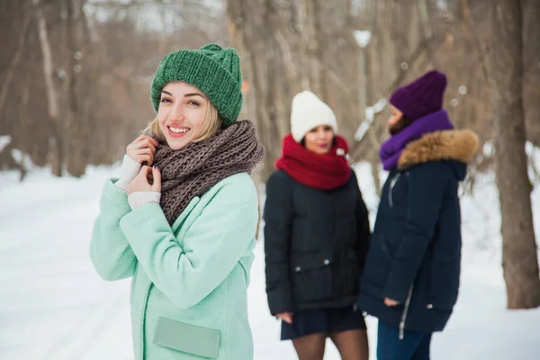 漂亮的年轻女子在绿色针织帽子和斯诺德在户外摆姿势 一个快乐的女孩微笑着对着镜头 两个女人的背景 — 图库照片