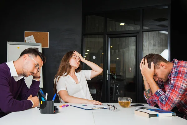 Three young businessmen have headache at office, sad failure. Disappointed people at work