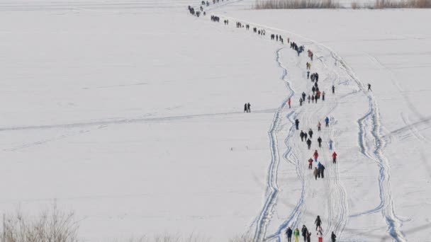 Personas irreconocibles cruzando gran río sobre hielo por pies en invierno . — Vídeo de stock