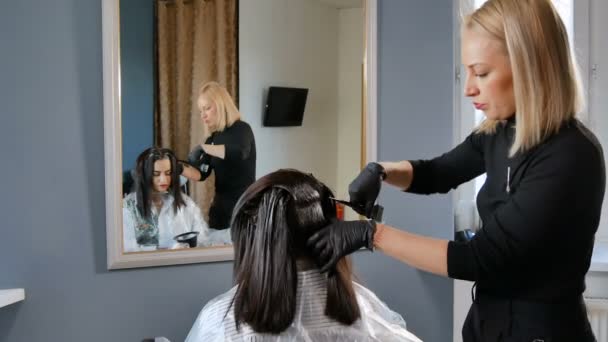 Женский парикмахер красит волосы в салоне красоты — стоковое видео