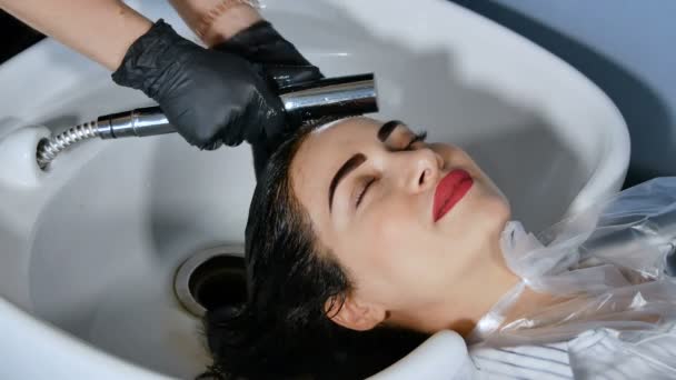 Женский парикмахер моет волосы, удаляет красящие красители — стоковое видео