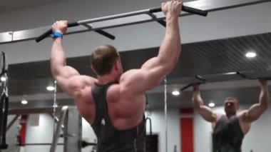 Fit kaslı adam spor salonunda spor ekipmanları sert tren, chin-ups