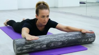 Rulo ve yoga mat ile pilates rehabilitasyon egzersizleri yapan Fit kadın.