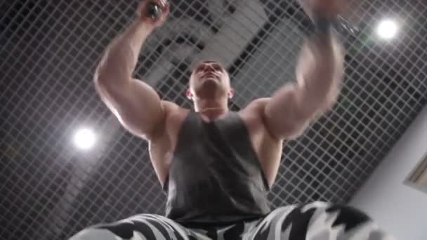 Strong young man exercising arms and shoulders with rope at gym. — Stock Video