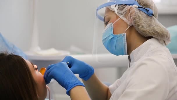 Dentista femminile cura la carie dentale con guarnizione leggera. — Video Stock