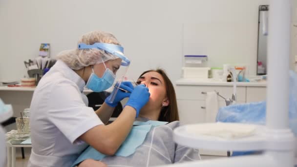 Estomatóloga femenina curando la cavidad dental con sello fotocurativo . — Vídeos de Stock