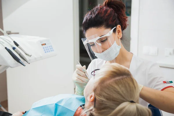 Zbliżenie ujęcia dentysty w masce ochronnej pracującego z ubytkiem zęba. — Zdjęcie stockowe