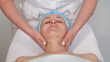 Kozmetik uzmanı hastaların yüzüne masaj uyguluyor..