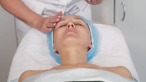 Kosmetolog stosujący serum na twarz pacjenta. — Wideo stockowe