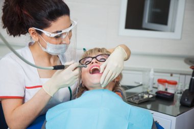 Diş boşluğuyla çalışan koruma maskeli diş hekiminin yakın çekimi..