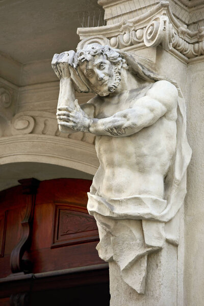 Bearded Atlant holding his head, as if he had a migraine. Detail of the facade. Bratislava.