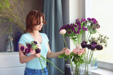 Çiçekçi işte. Mavi bir t-shirt kızıl saçlı kız, gül alışılmadık bir gelinlik buketi oluşturur, alstroemeria, sulu, devedikeni ve scabiosa. Çiçek atölyesi.