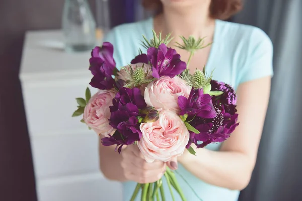 Çiçekçi gül, alstroemeria, dikenler ve sulu alışılmadık buket bitirir. Kadın ellerindeçiçekler yakın.