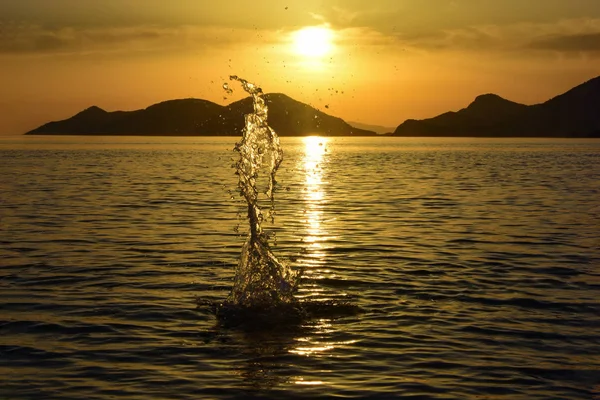 Suya atılan bir taştan hafif bir sıçrama. Oludeniz sahilinde gün batımı. Türkiye.