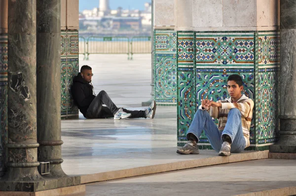 İki genç Hassan Ii cami galerisinin gölgesinde dinleniyor. Casablanca. Fas. Kuzey Afrika. 29 Aralık 2012.