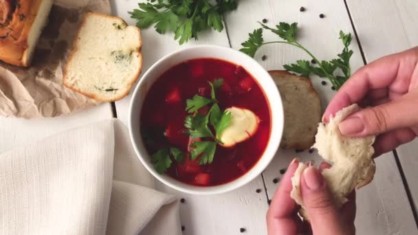A girl breaks soft fresh bread near a plate of vegetable beet soup — Stock Footage A girl breaks soft fresh bread near a plate of vegetable beet soup Royalty Free Stock Video