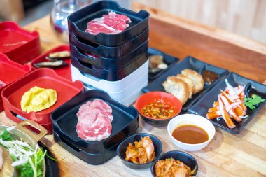 Köfte, hamur köftesi, kimchi, yengeç çubuğu, sebze ve ahşap bir masada servis edilen soslar da dahil olmak üzere, Asya mutfağını ve yemeklerini temsil eden çeşitli malzemeler..