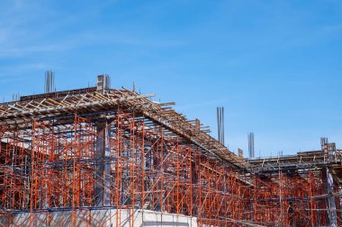 Açık mavi gökyüzü altındaki bir inşaat sahasının çelik iskelesi ve beton iskeleti, yapı, mimari, endüstri ve kentsel gelişimi temsil ediyor..