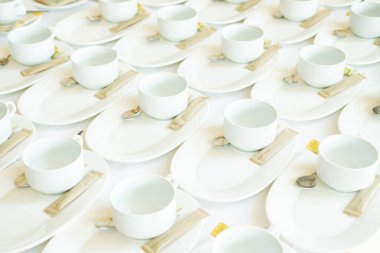 Beyaz seramik kahve fincanları, beyaz tabaklar üzerinde, kaşık ve şeker paketleri ile, kahve molası ya da konferans için hazır, konukseverliği ve profesyonel hizmeti sembolize ediyor..