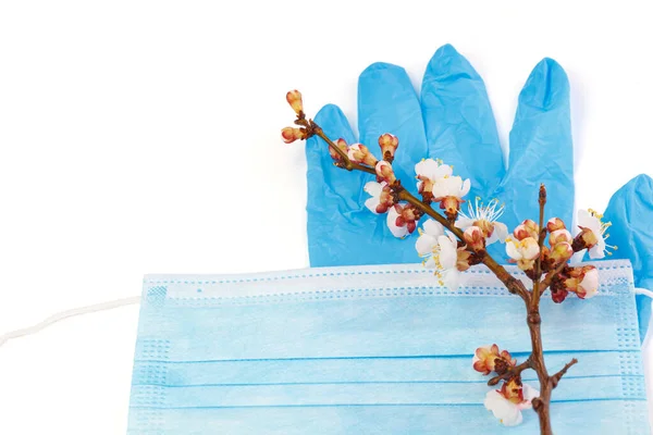 The concept of comparing prevention and health with spring in nature. Means of preventing viral diseases. Medical mask and rubber gloves on a white background.  Corona virus.