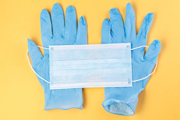 Medical masks and two rubber gloves on a yellow background. Corona virus. Healthcare and medical concept. Close up view of medical protection of face and hands . mask textile filter