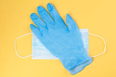 Sarı arka planda tıbbi maskeler ve lastik eldivenler. Corona virüsü. Sağlık ve tıbbi konsept. Yüz ve ellerin tıbbi korunmasına yakından bakın. maskeli tekstil filtresi