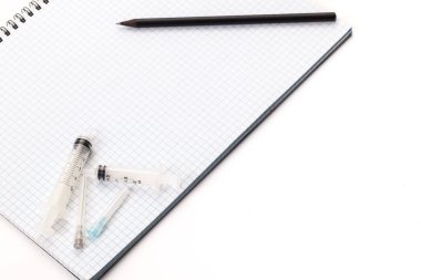 Tıbbi enjeksiyonlar için iğneler beyaz arka planda izole edilmiş defterde. Metnin ya da imzan için boş yer var.