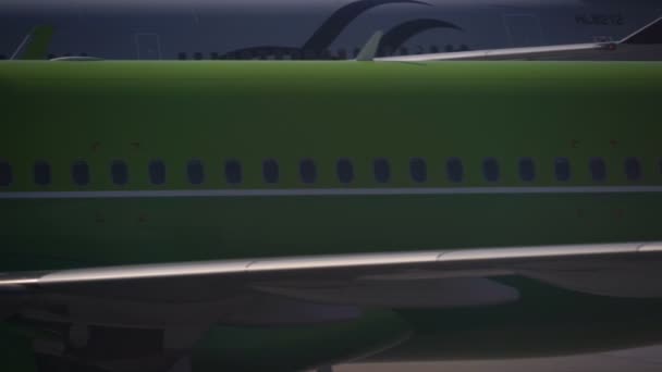 Close up vista lateral um plano verde está se movendo ao longo da pista e atrás dela a cauda de outro avião — Vídeo de Stock