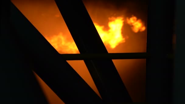 Lågor brinner bakom metallpelarna i en industribyggnad — Stockvideo