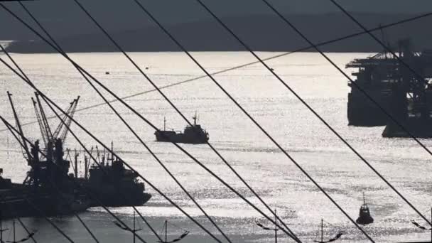 A small cargo ship sails through the Strait from the port in silhouette — Stock Video