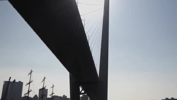 Benedenaanzicht van enorme brug in de zon tegen de achtergrond van stedelijke nieuwbouw — Stockvideo