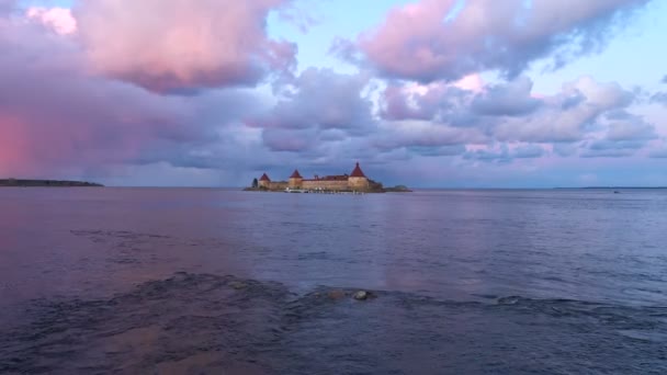 Крепость на воде с башнями на фоне красивых облаков, освещенных закатом солнца — стоковое видео