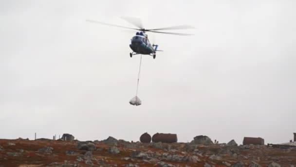 Mi-8 helikopterleri kargo beyazı çantalarla iniyor. Altında sallanıyorlar, iplere asılıyorlar. — Stok video