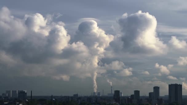 Пар от градирен электростанции, расположенной за городом, поднимается вверх, образуя большое облако. На переднем плане находятся различные здания различной высоты — стоковое видео