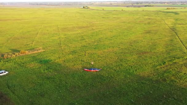 모터 패러글라이더가 전장에서 이륙하기 시작하지만, 조종사는 날개와 날개가 풀밭으로 떨어지는 실수를 저지릅니다. 공중에서 본 광경. — 비디오