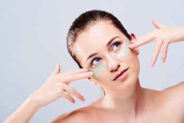 Göz cilt güzellik. Güzel genç kadın model doğal makyaj ve göz bakımı hidrojel yamalar yüzündeki gri arka plan üzerinde hyaluronik asit ile altında portresi. Yüksek çözünürlük.