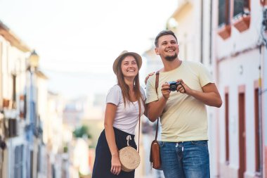 Gülüyor ve film kamera ile eski İspanyol şehir fotoğrafını çekmek genç mutlu çift. Şık erkek ve kadın üzerinde tatil İspanya, Europe. Turizm ve seyahat kavramı.